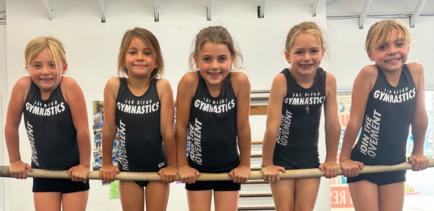 Five girls balancing on a gymnastics bar