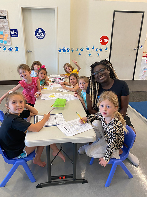 A preschool teacher sitting with her students