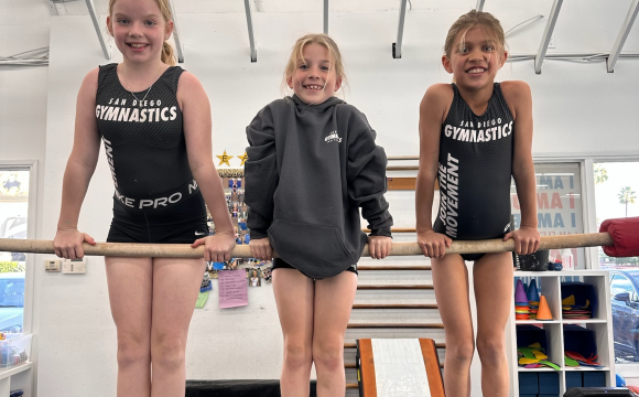 Three girls balancing on the gymnastics pole