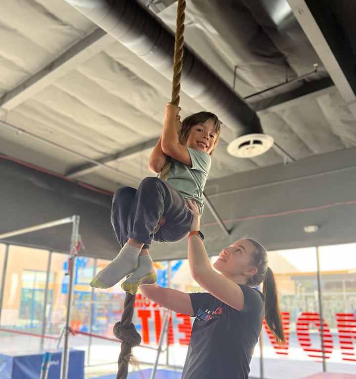 An instructor helping a younger student on a rope exercise