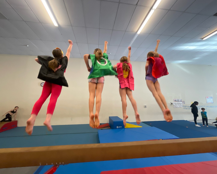 A group of girls jumping together with an arm stretched out