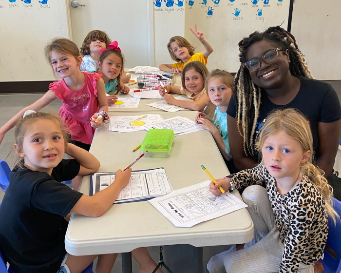 A teacher sitting with her preschool students