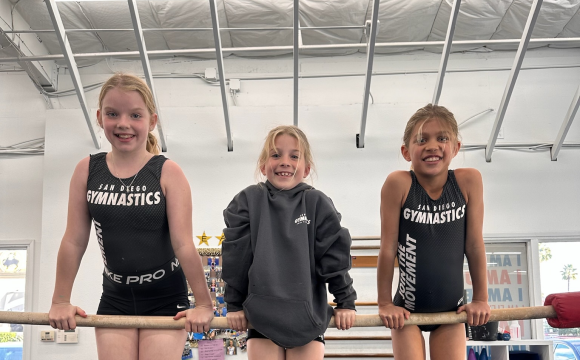 Three girls balancing on the gymnastics pole