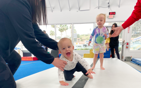 A baby being guided as they learn to crawl