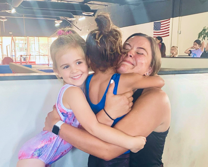 Two students hugging an instructor