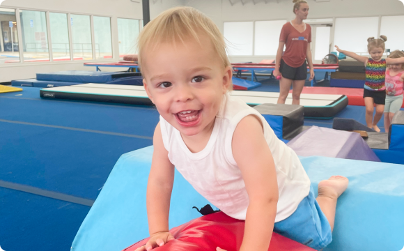 A toddler crawling over gym mats