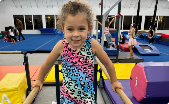 A kid holding themselves up on gymnastic bar