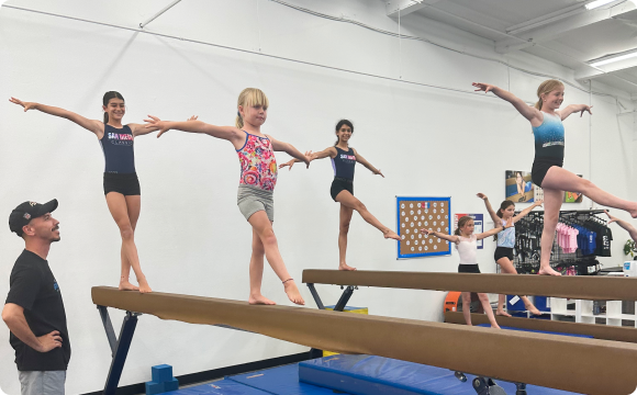 Kids balancing on a post together as an instructor observes