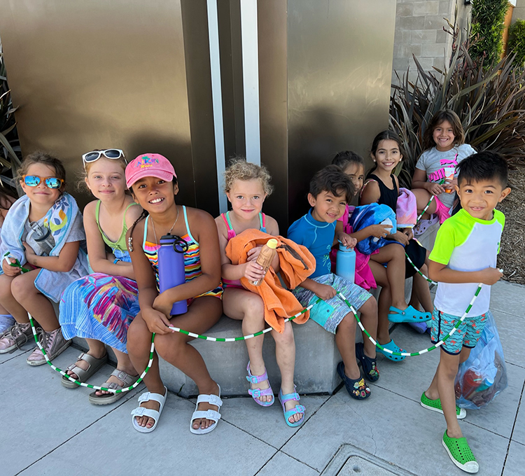 A group of kids sitting together holding a jump rope